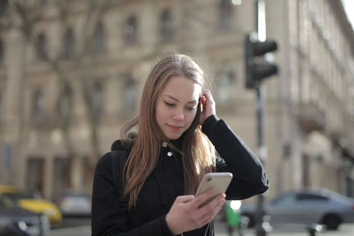 Woman on a city street looking down at her phone