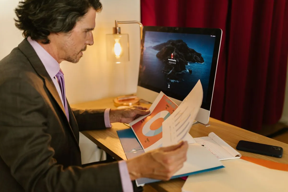 Man in a suit at a desk studying printed pie and bar charts