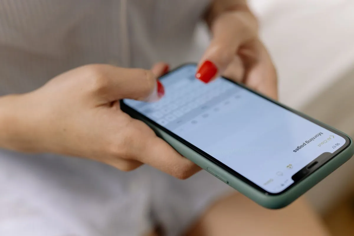 Hands holding a phone sideways, thumbs typing on the on-screen keyboard