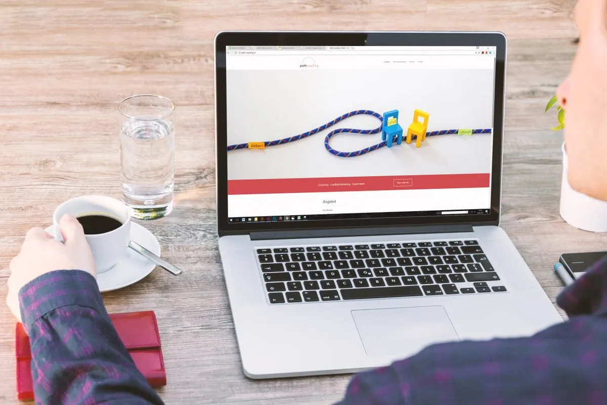 Person holding a coffee cup views a website homepage on a laptop