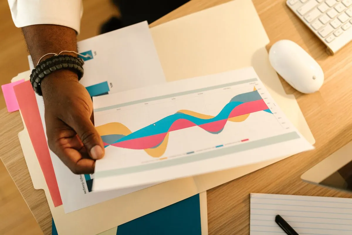 Hand lifting a printed chart page from file folders on a wooden desk