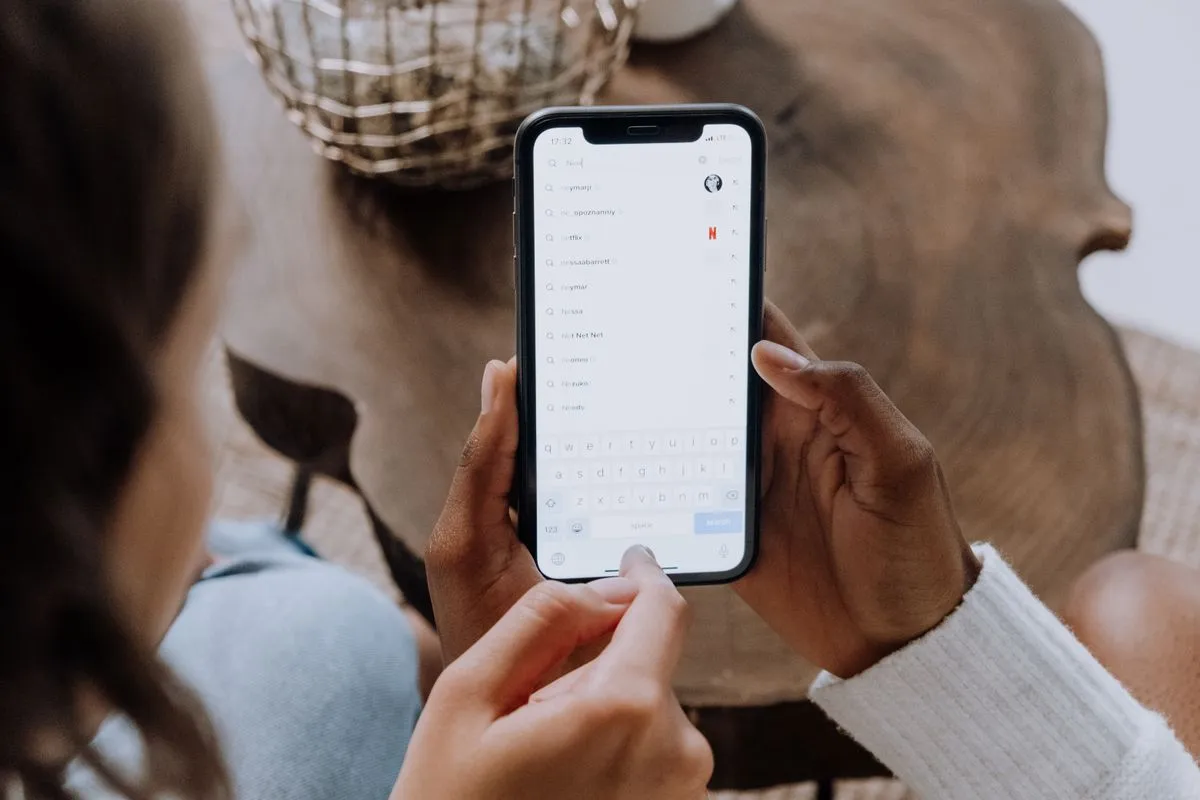 Hands holding a phone, finger typing into an open search bar