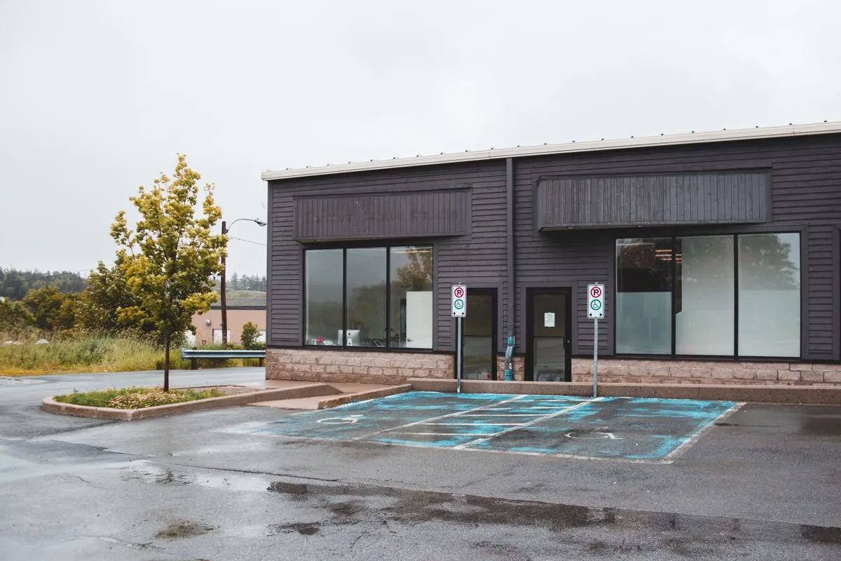 Dark-sided single-story building with blank sign panels above empty accessible parking